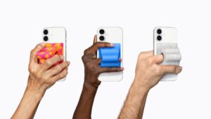 Three hands holding iPhones with accessibility grip accessories on a white background, Apple WWDC 2026 preview