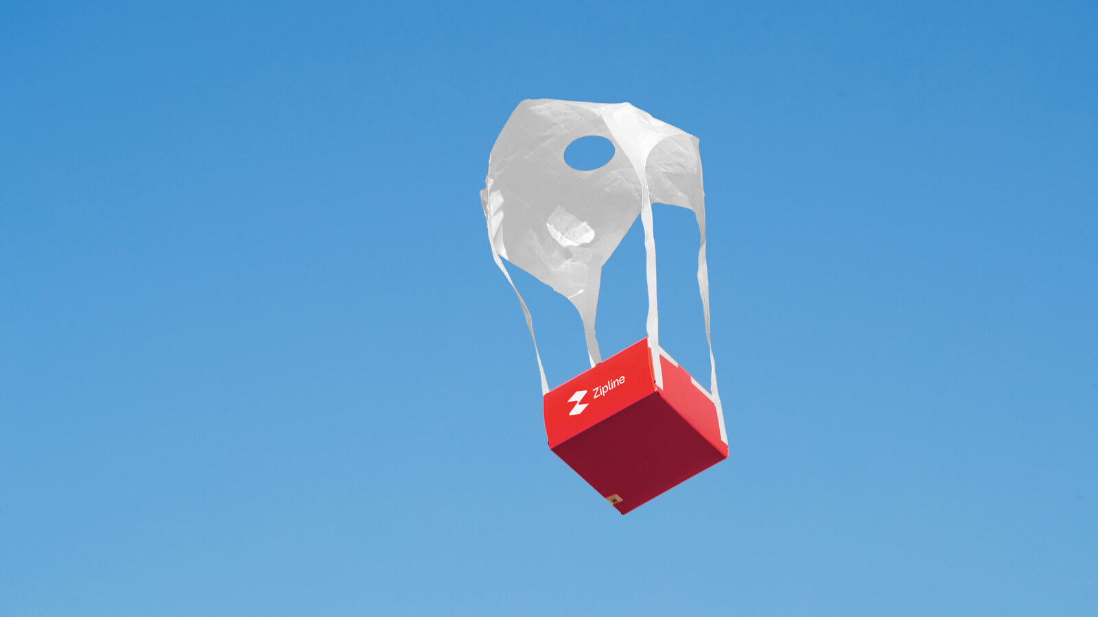 Zipline drone delivery package descending on its mini parachute