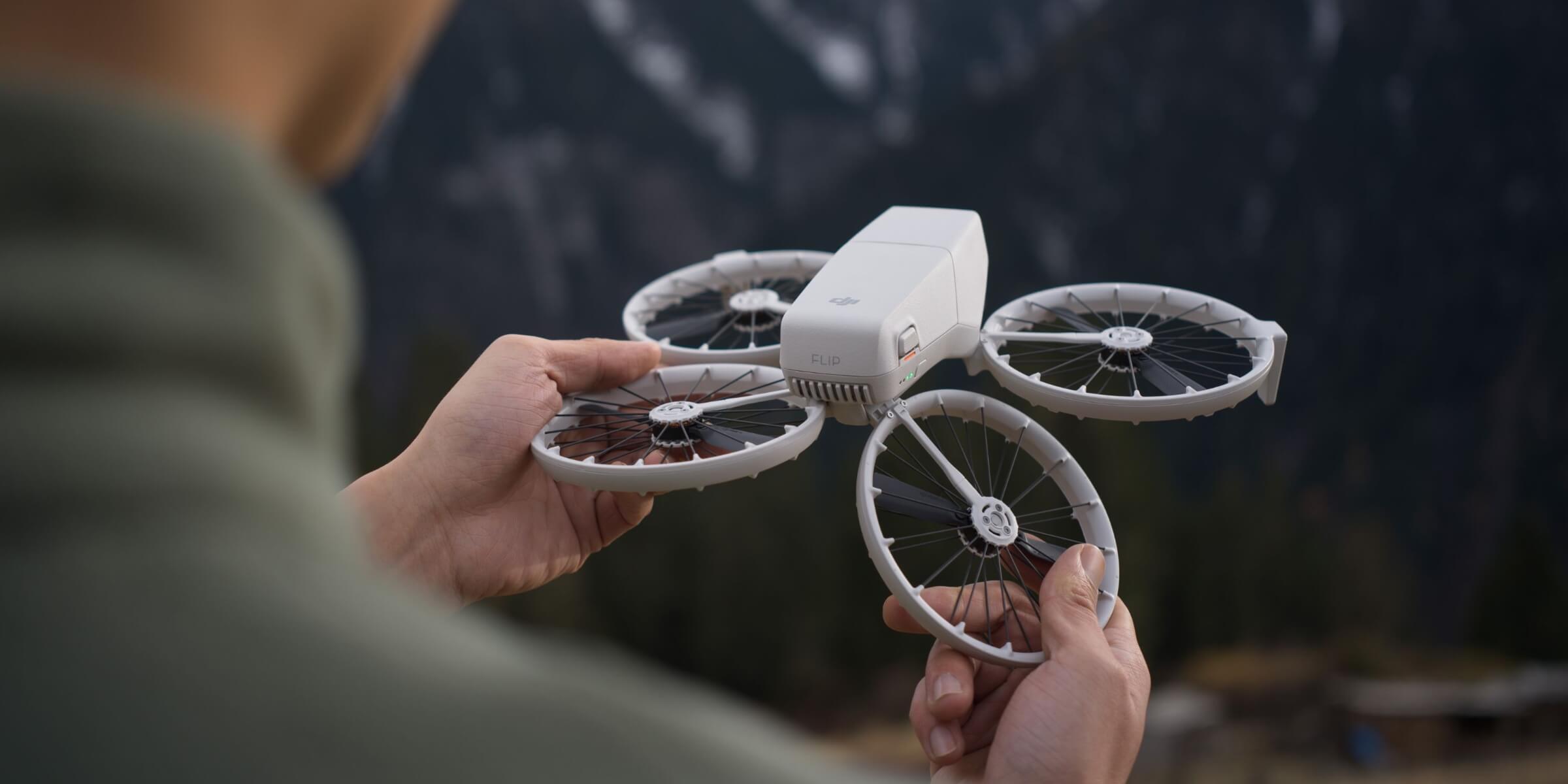 DJI Flip folding drone with circular propeller guards held in a hand outdoors
