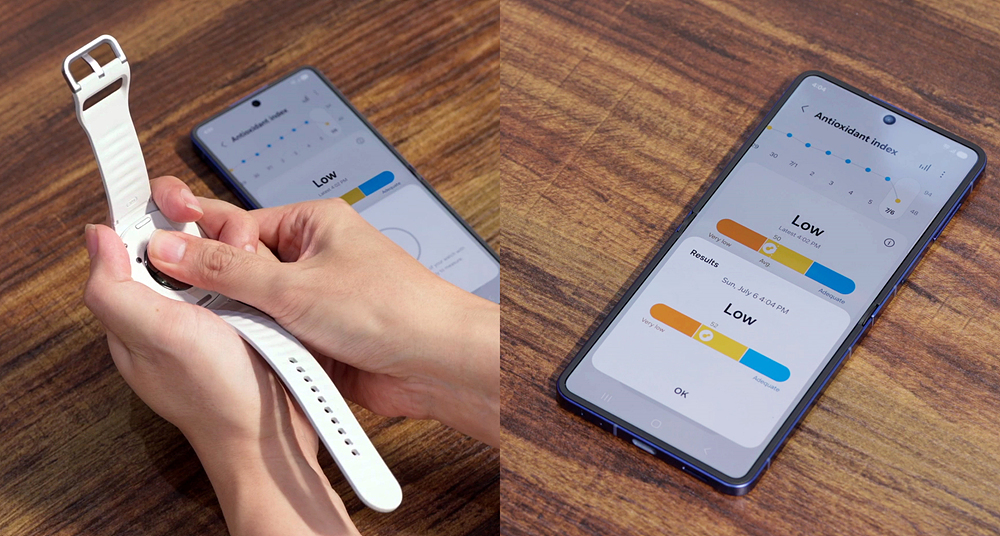 A person holding the Galaxy Watch 8 and pressing a fingertip to the rear sensor to take an Antioxidant Index reading next to a phone showing the result