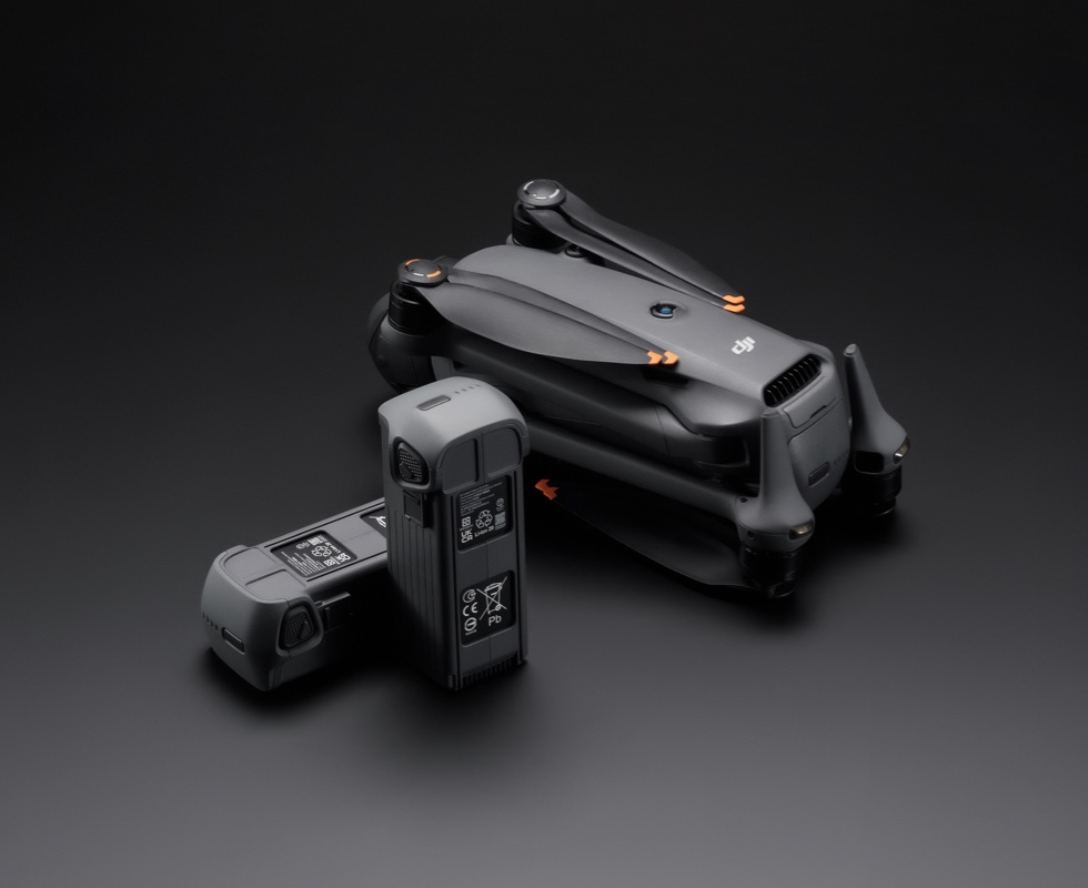 DJI Mavic 4 Pro folded for transport sitting next to its Intelligent Flight Battery on a grey surface