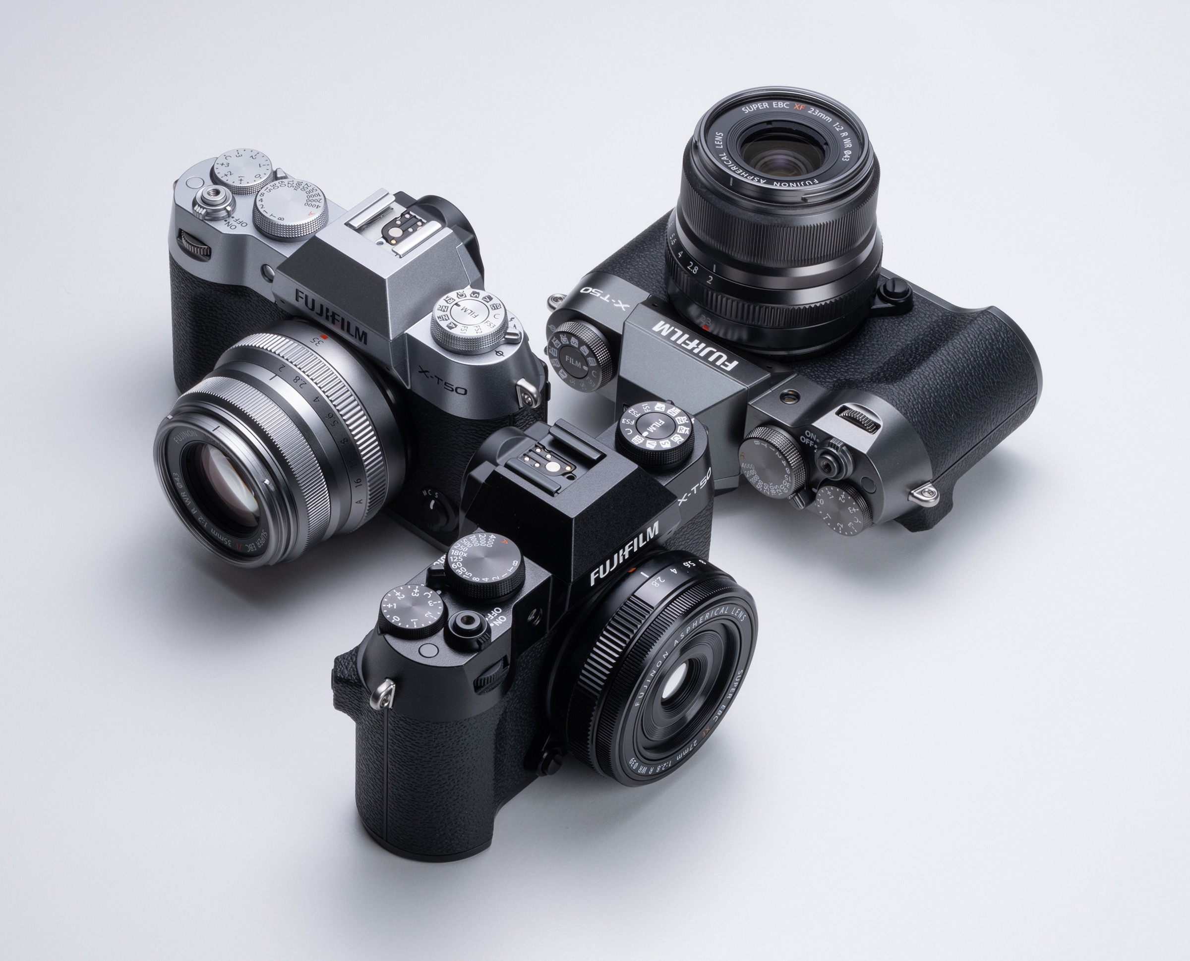 Fujifilm X-T50 shown in silver, black and charcoal finishes arranged on a white surface