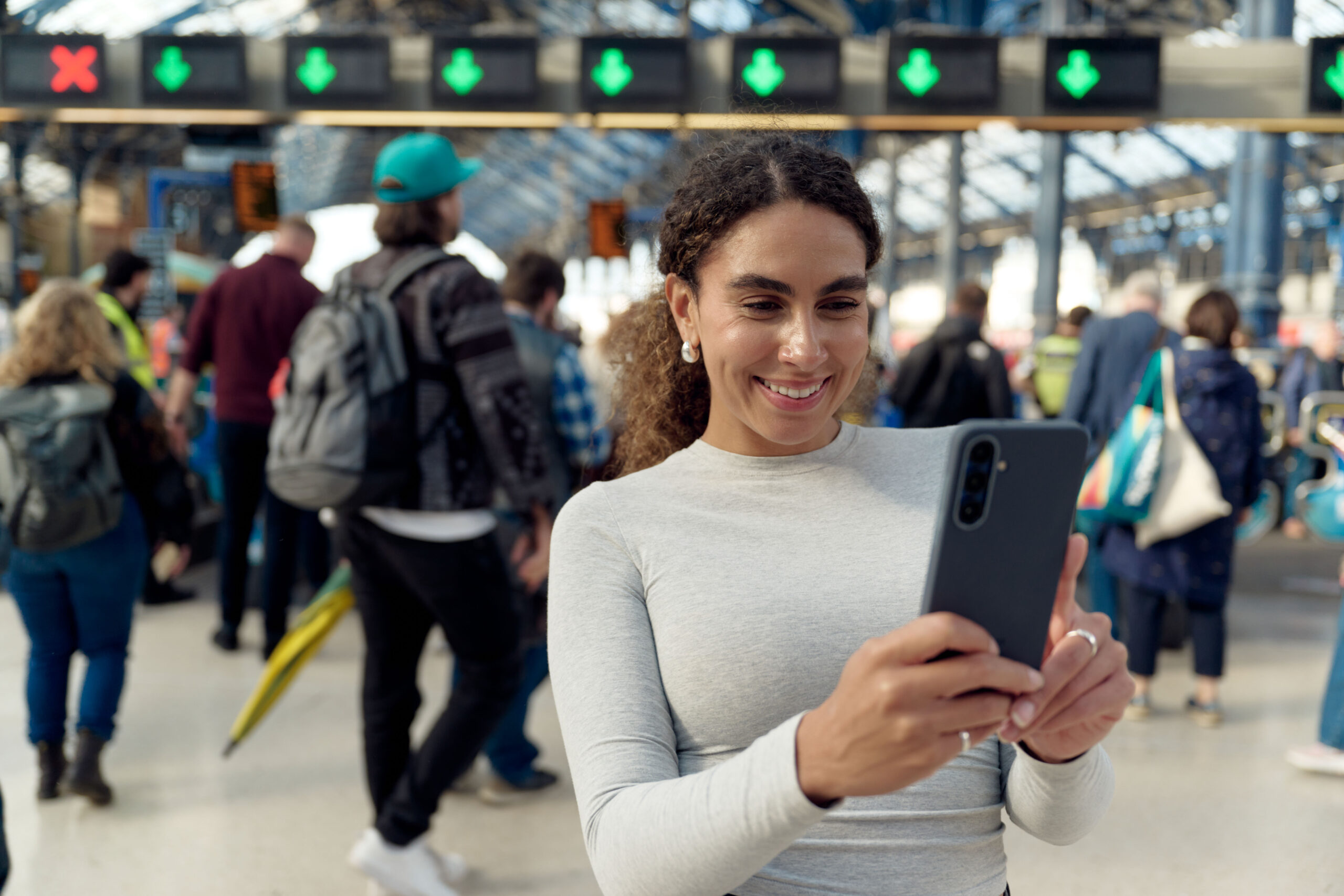 Woman using a smartphone on the EE network at a busy UK railway station