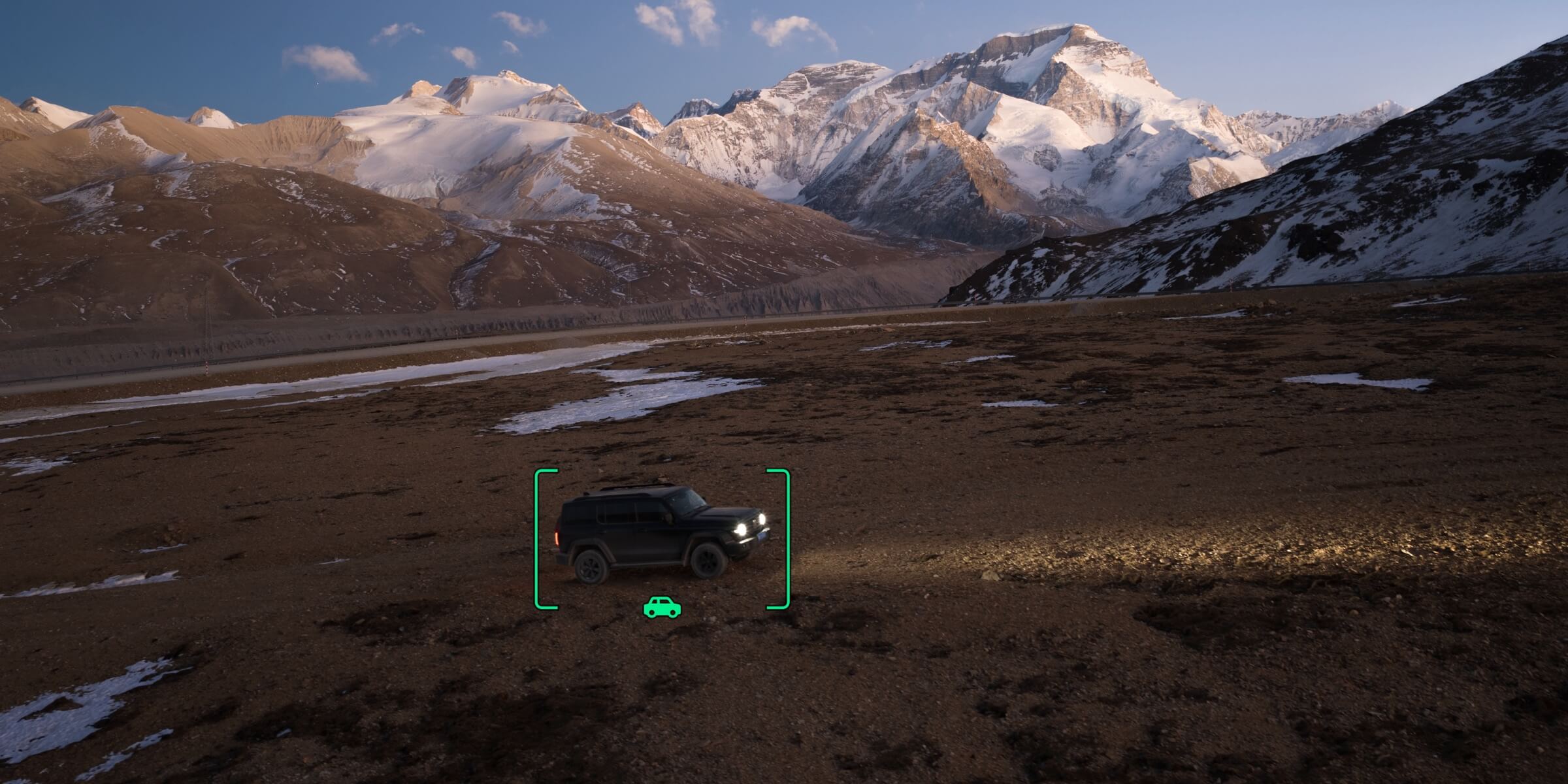 Aerial view from the DJI Mavic 4 Pro tracking a 4x4 vehicle in a mountain valley with a green tracking box on screen