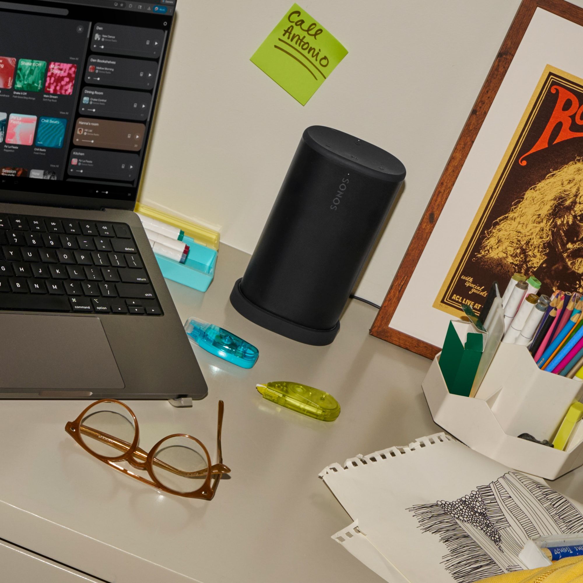 Black Sonos Play speaker standing upright on a wooden desk next to a laptop