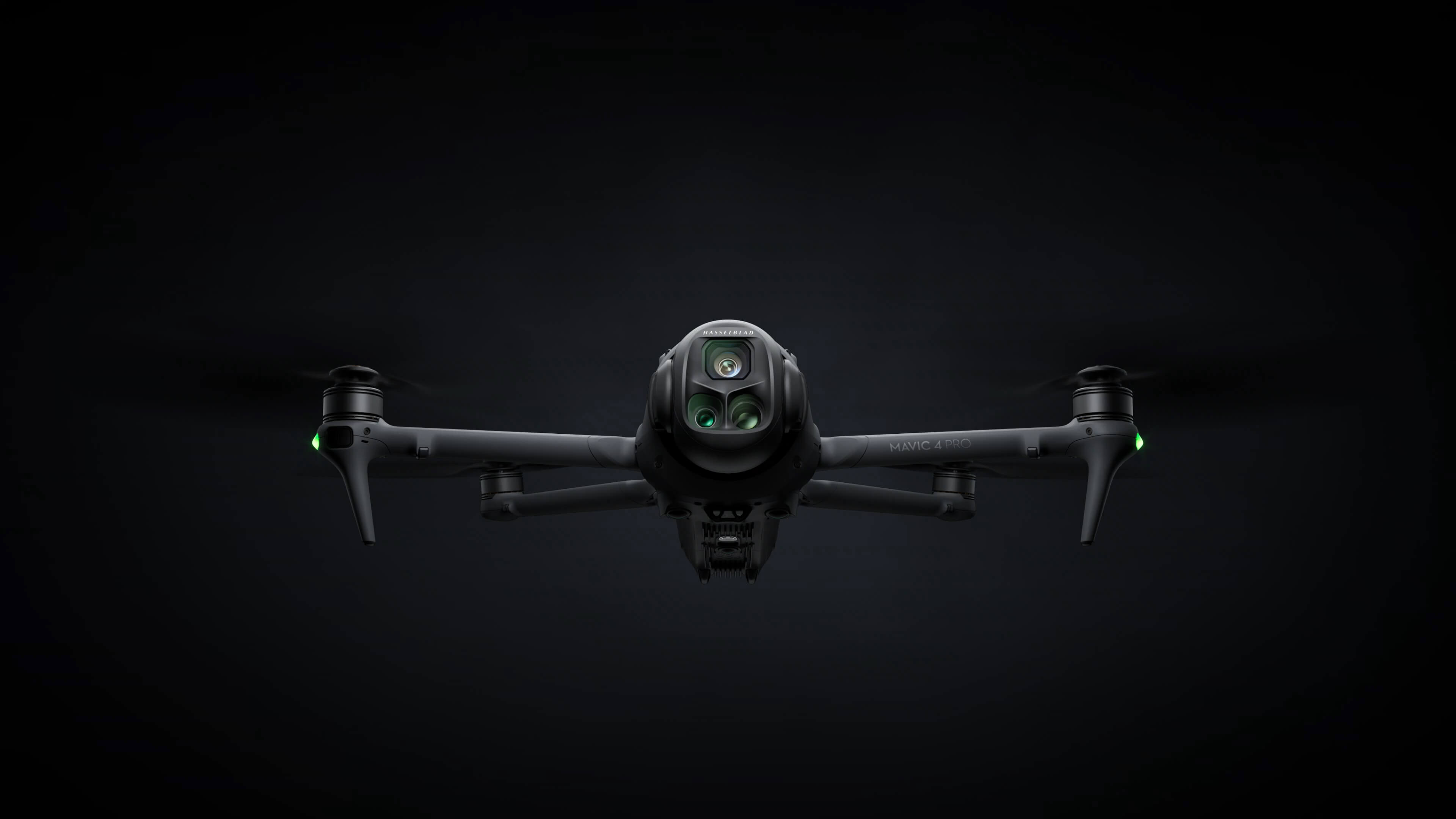DJI Mavic 4 Pro hovering head-on against a dark background with green status lights lit