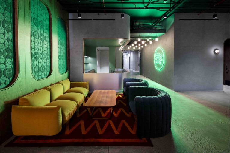 Spotify lounge interior with the green Spotify logo glowing on a concrete wall