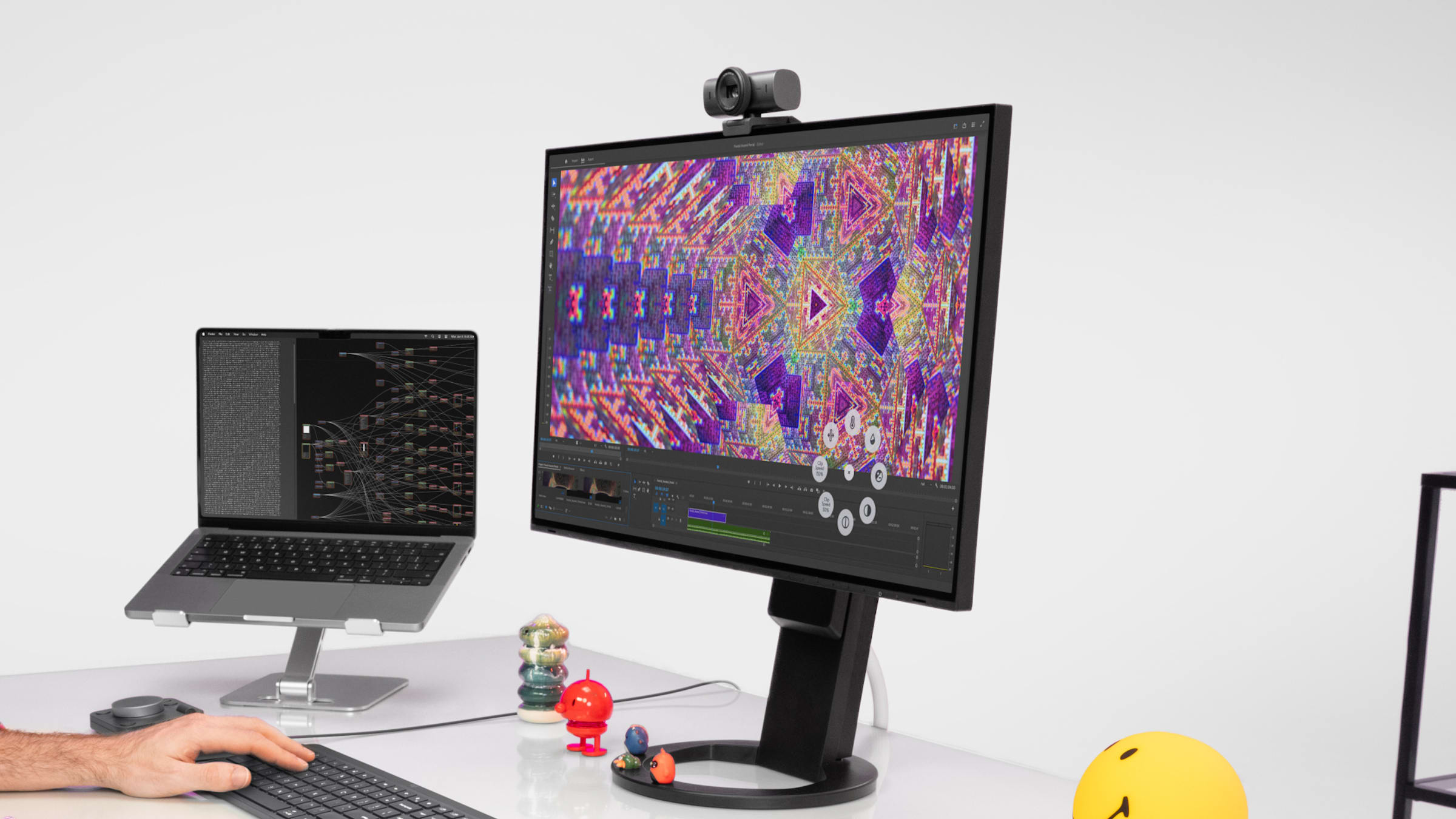 Logitech MX Master 4 in use at a desk with a monitor, webcam and laptop in a creative workspace