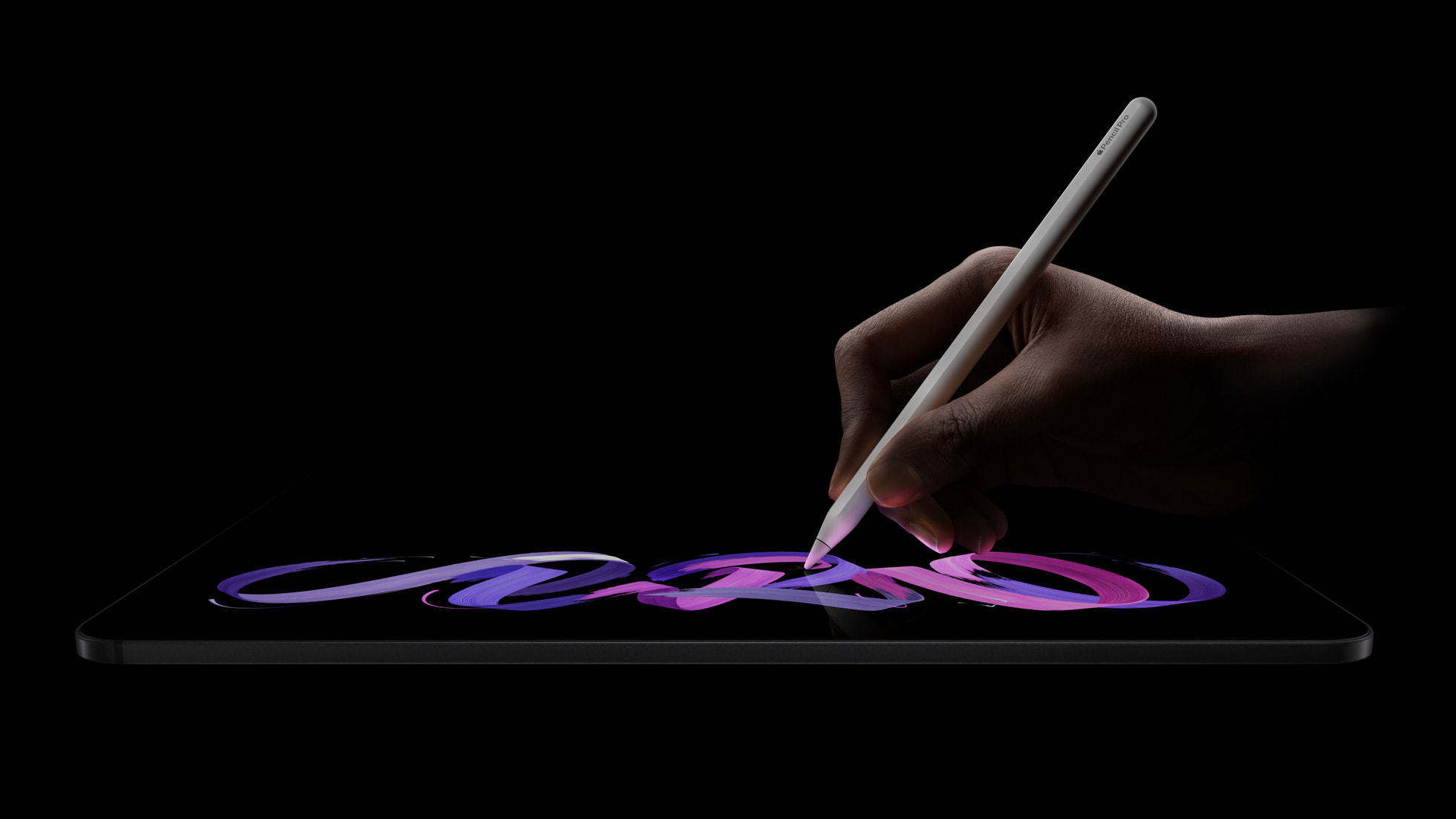 Apple Pencil Pro drawing a colourful pink and purple brushstroke on the iPad Pro M5 OLED display