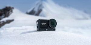 DJI Osmo Action 6 action camera resting on snow with a mountain backdrop