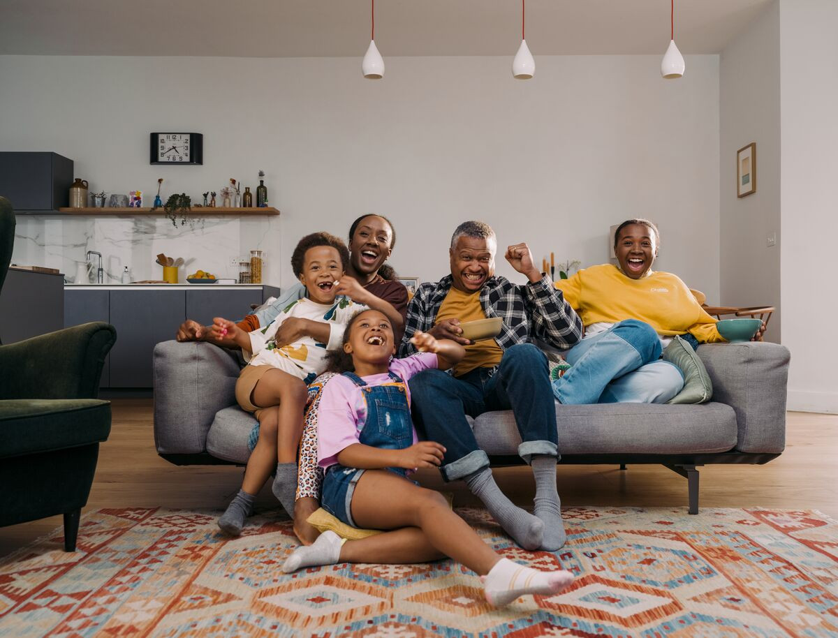 Family of five cheering on a sofa while watching content streamed on EE at home