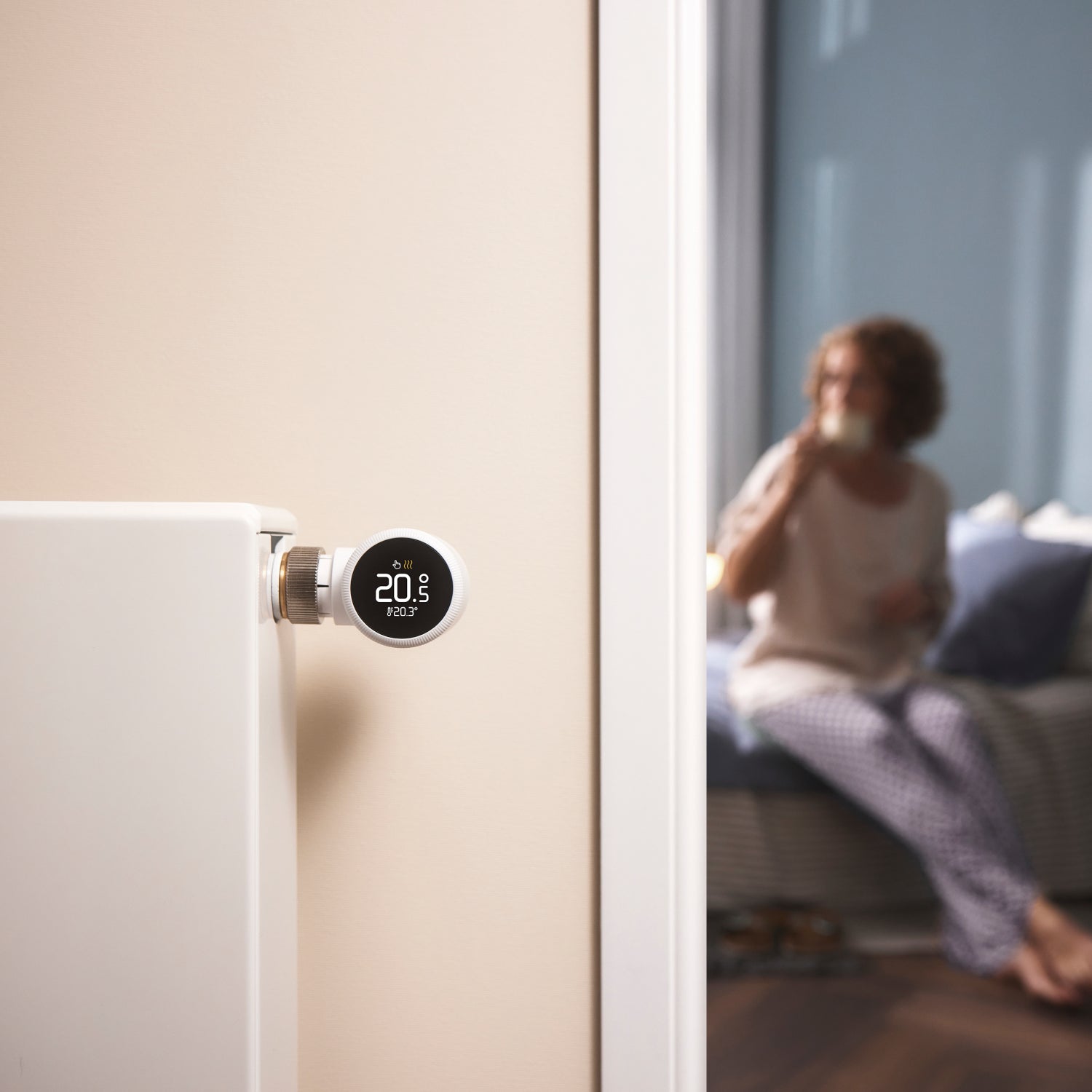 A tado Smart Radiator Thermostat X fitted to a white radiator valve in a bright living room