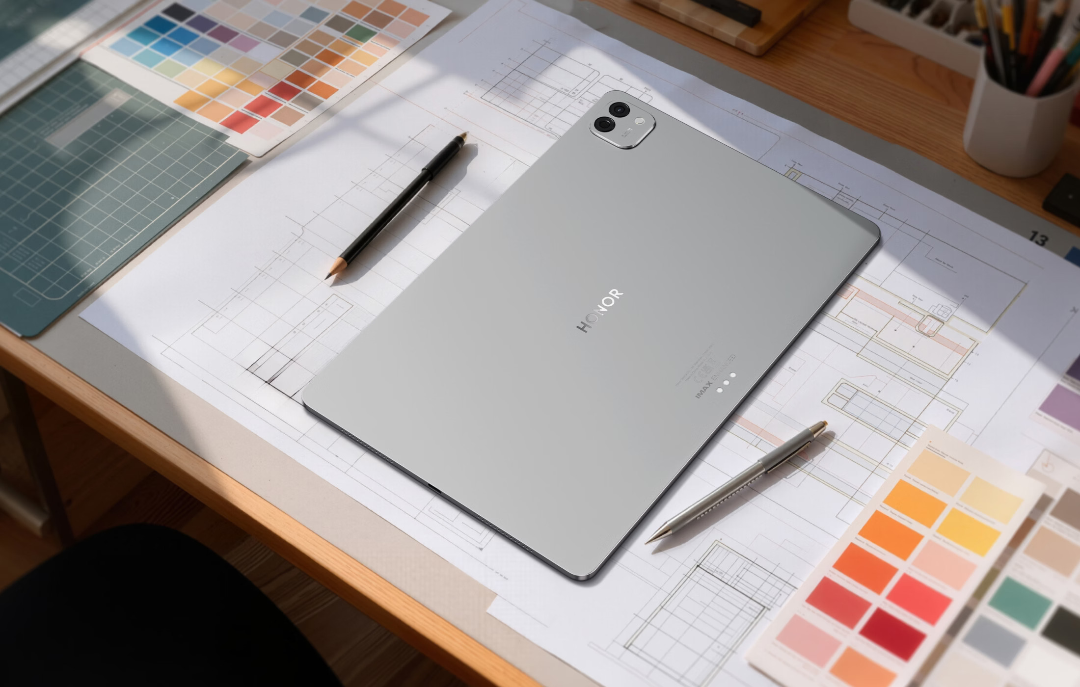 HONOR MagicPad 4 in grey lying on architectural drawings with colour swatches