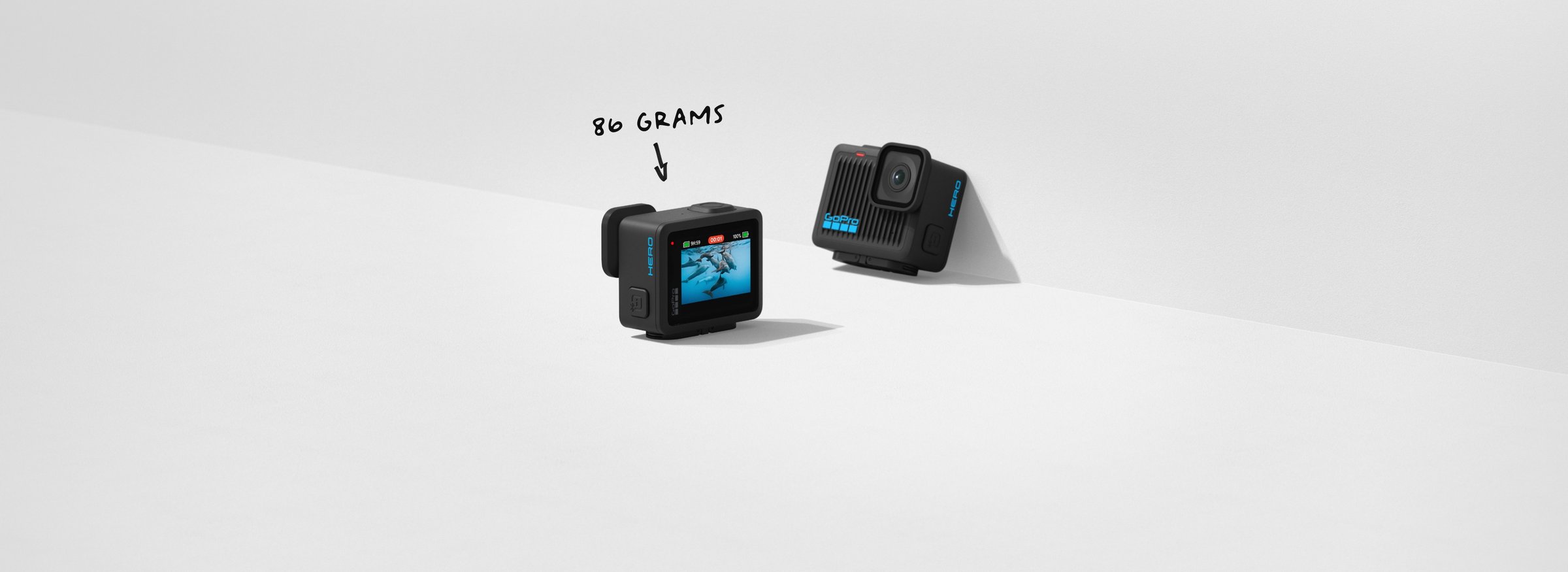 Two GoPro HERO entry action cameras on a white surface showing the compact 86 gram body front and rear