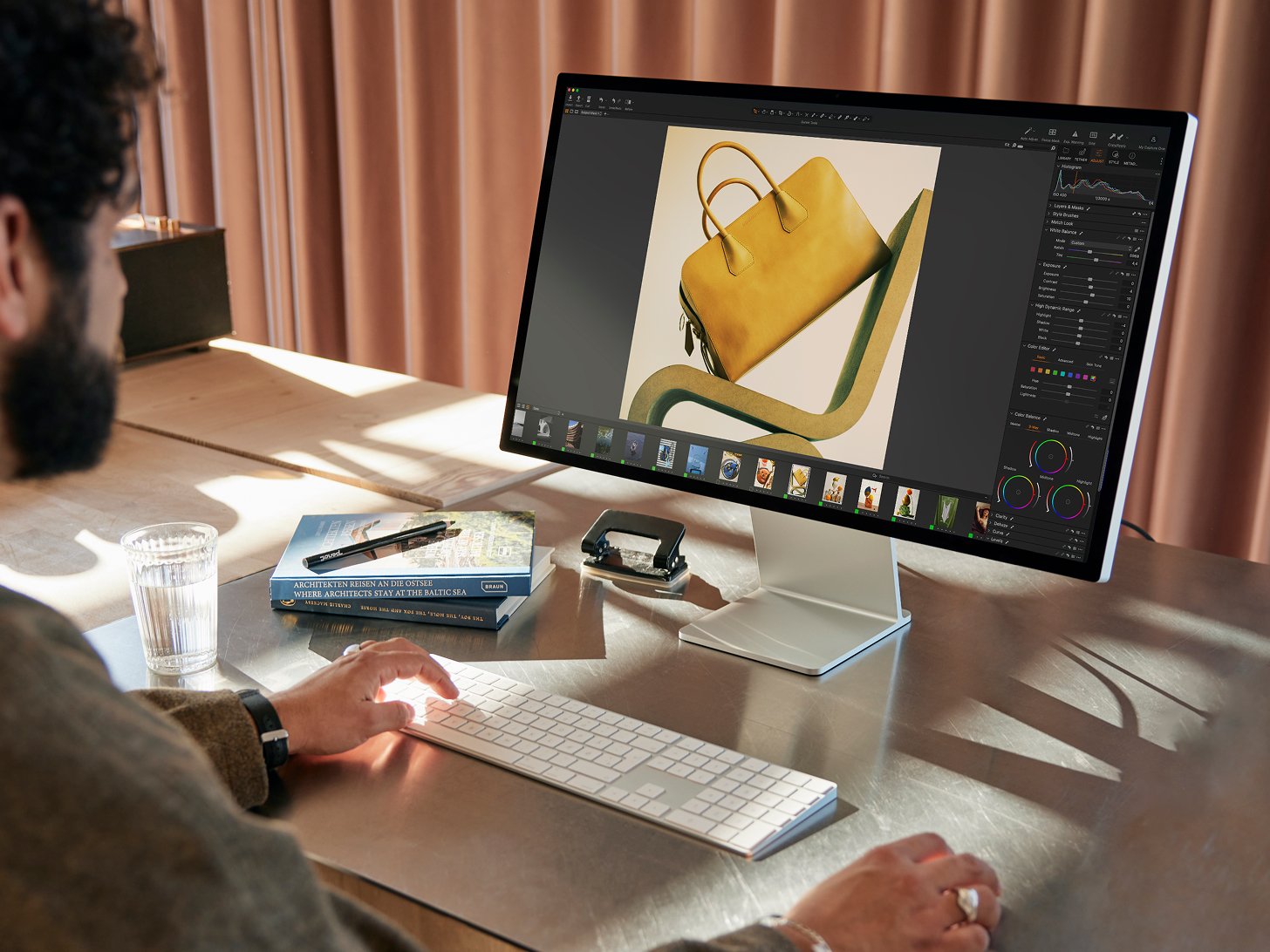 Photographer editing a yellow handbag product shot in Capture One Pro on a desktop display