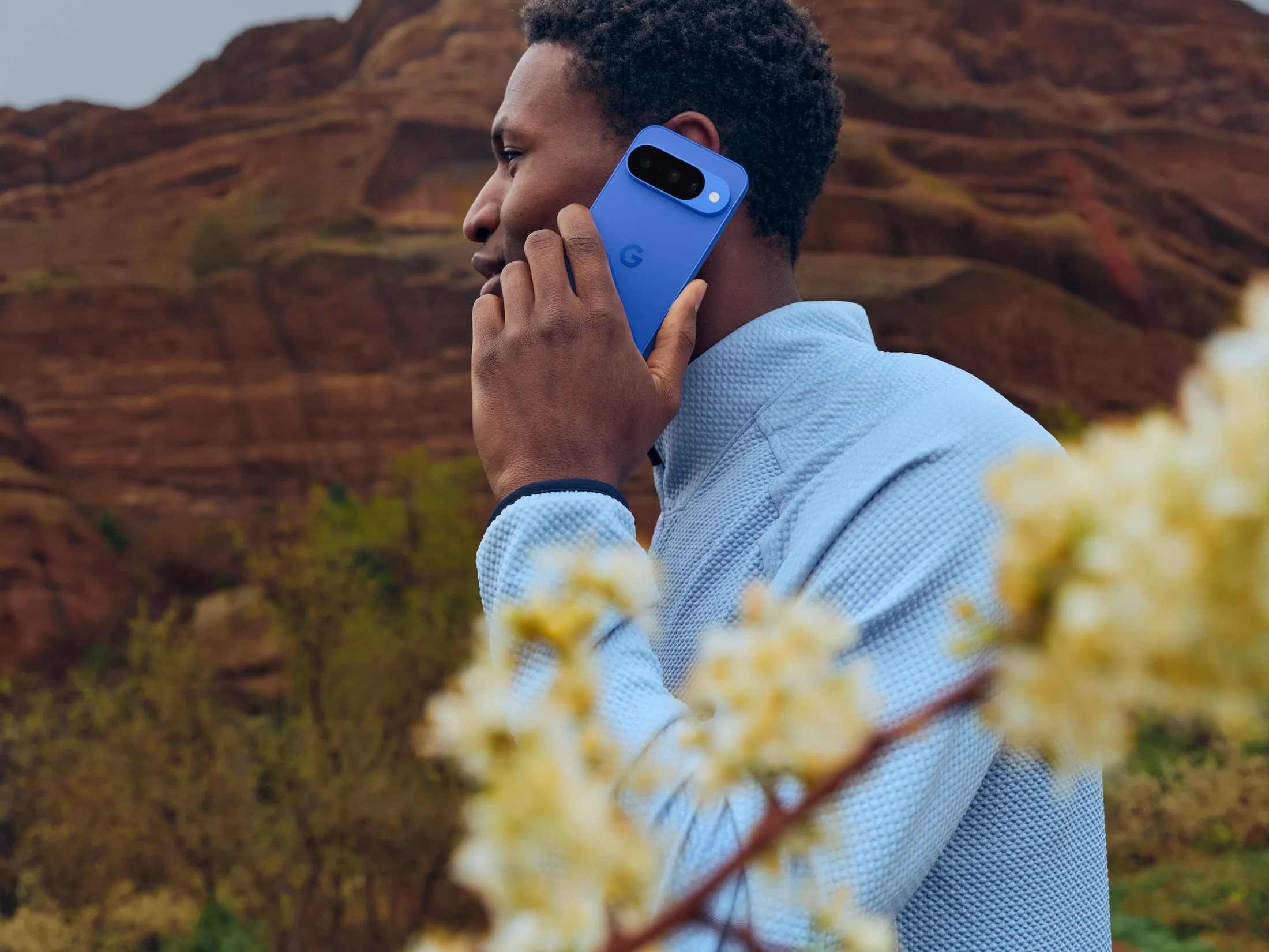 Person holding the current Google Pixel 10 in Indigo against rock scenery