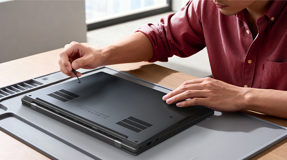 Hands using a tool to open the back panel of the Lenovo ThinkPad X1 Carbon Gen 14