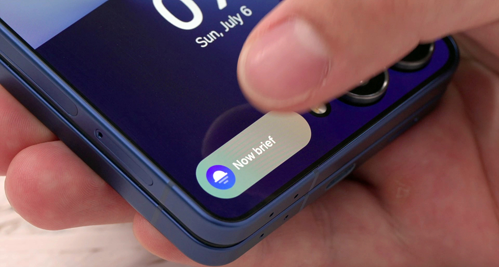 Close-up of a thumb tapping the Now Brief widget on a current Samsung Galaxy Z Flip cover screen