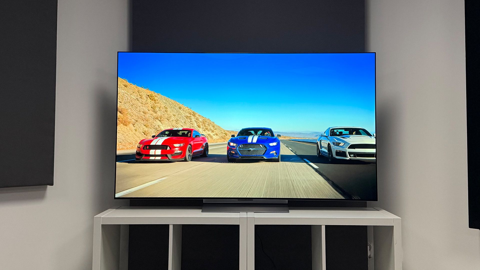 OLED television displaying three performance cars on a desert highway