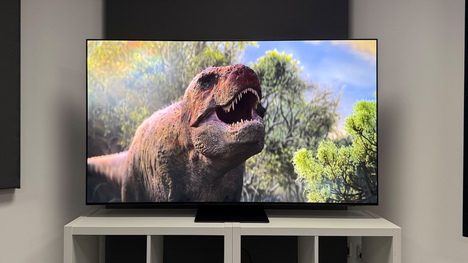 Samsung S95F mounted flush to a wall with the One Connect box routing cables aside, mid-game